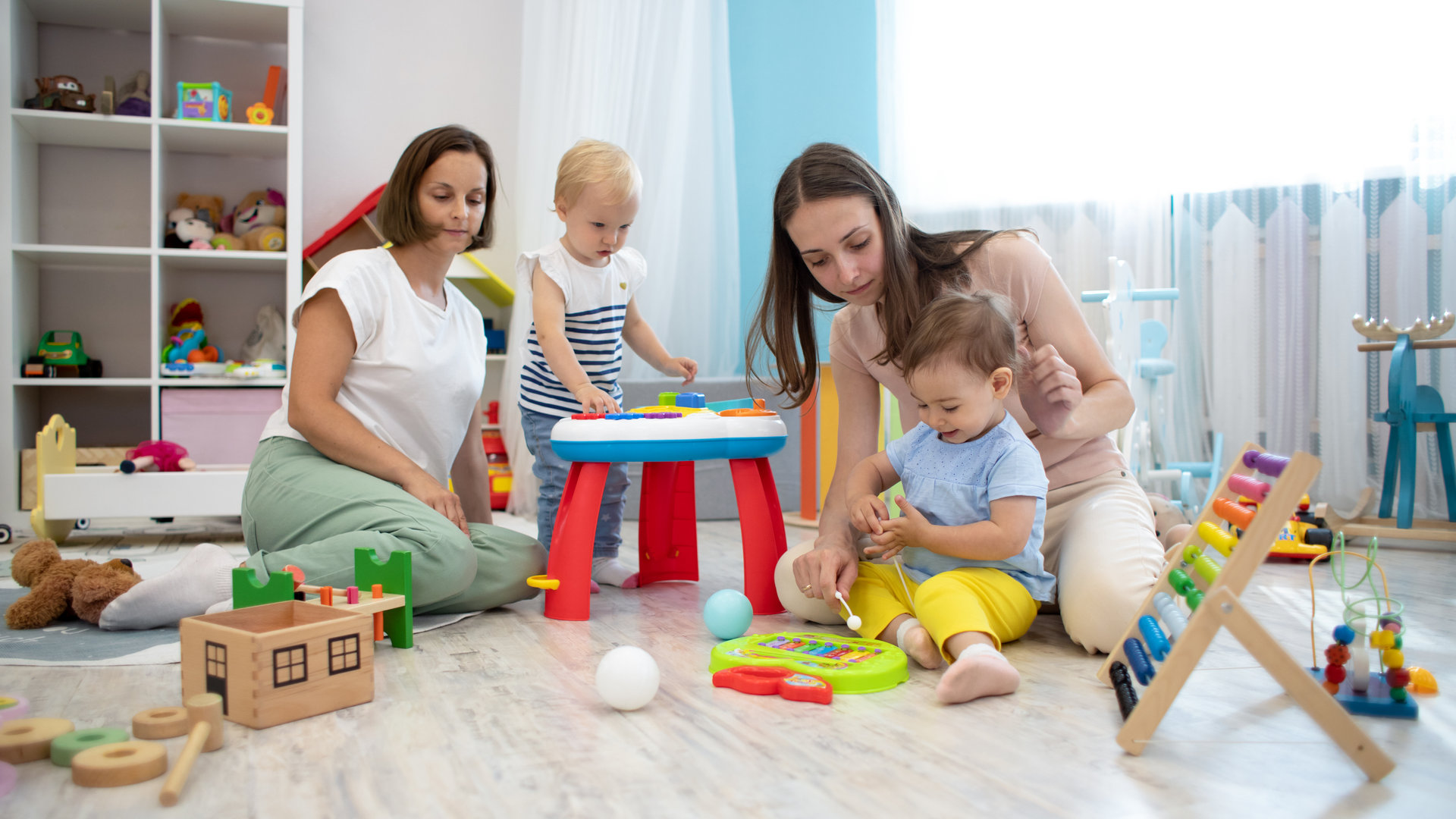 babies with adults playing in playroom or nursery