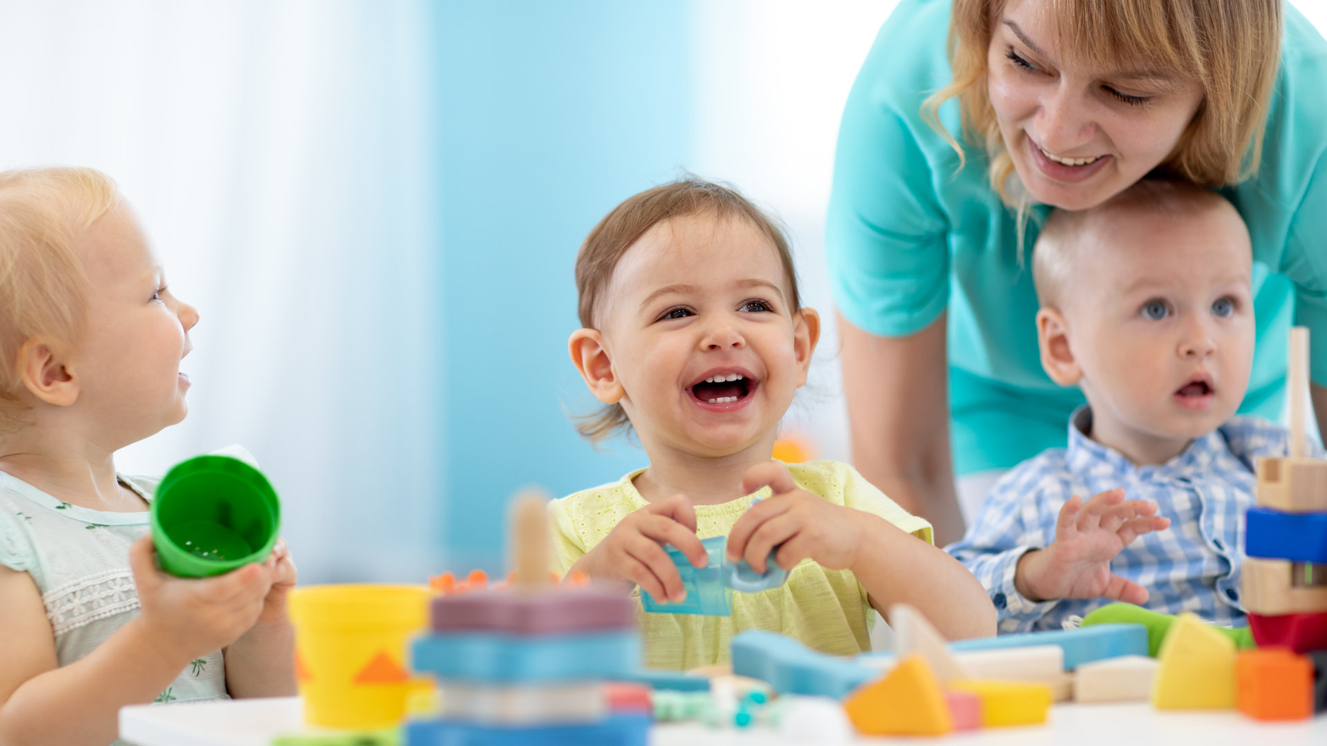 Babies play with teacher in nursery or creche